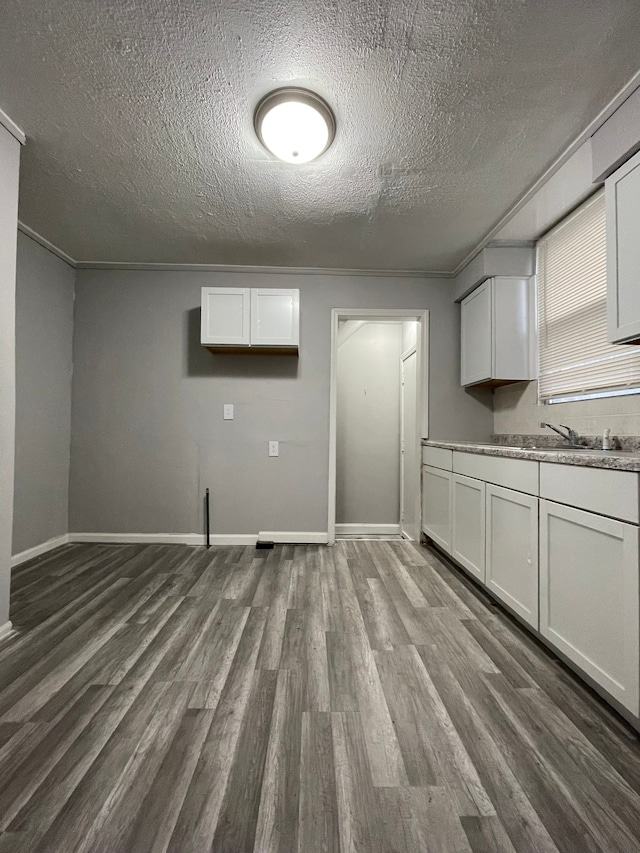 kitchen featuring white cabinets, ornamental molding, a textured ceiling, and hardwood / wood-style floors