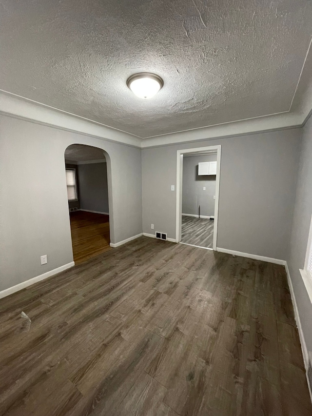 spare room featuring a textured ceiling and dark wood-type flooring