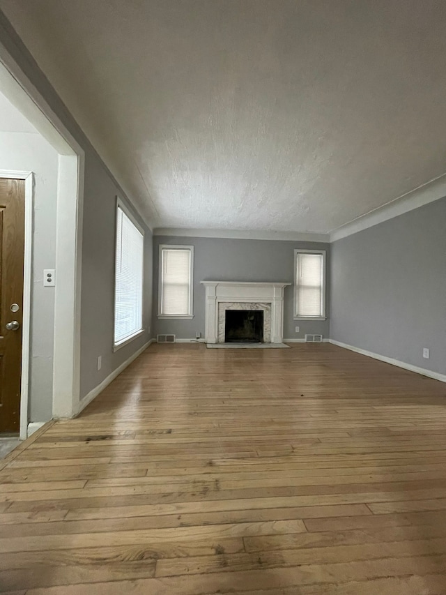 unfurnished living room with light wood-type flooring and ornamental molding