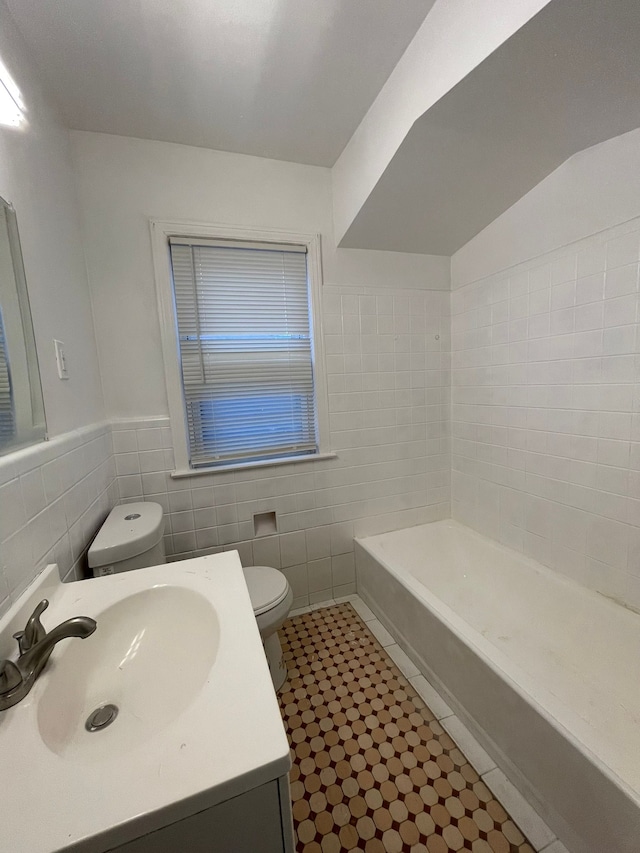 bathroom featuring vanity, toilet, tile walls, and a tub