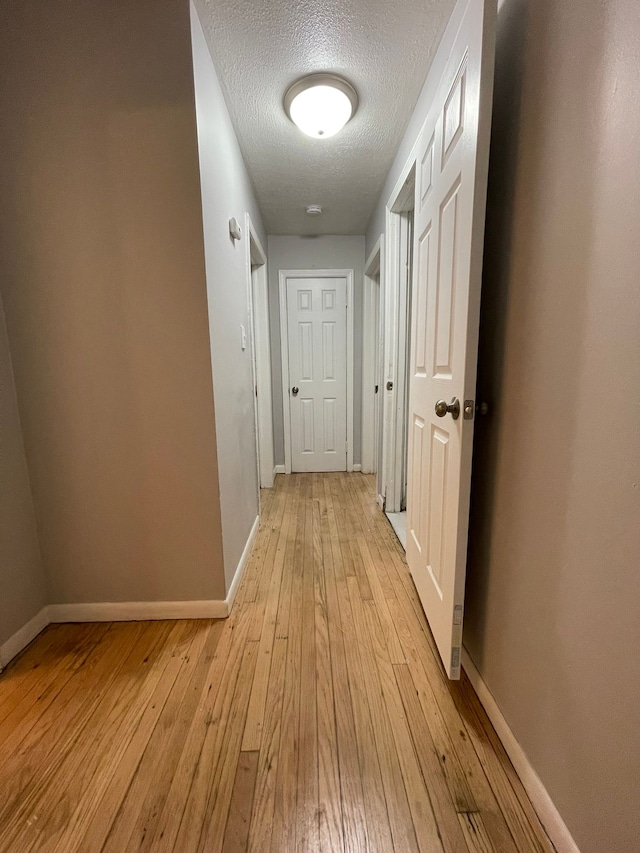 corridor featuring a textured ceiling and light hardwood / wood-style flooring