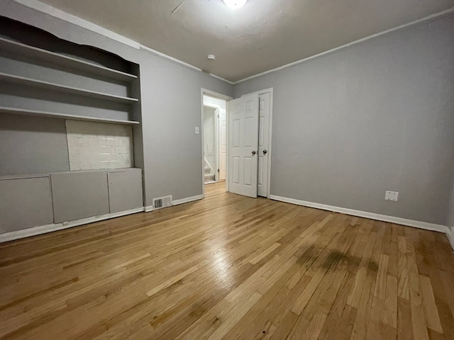 unfurnished bedroom with ornamental molding and light wood-type flooring