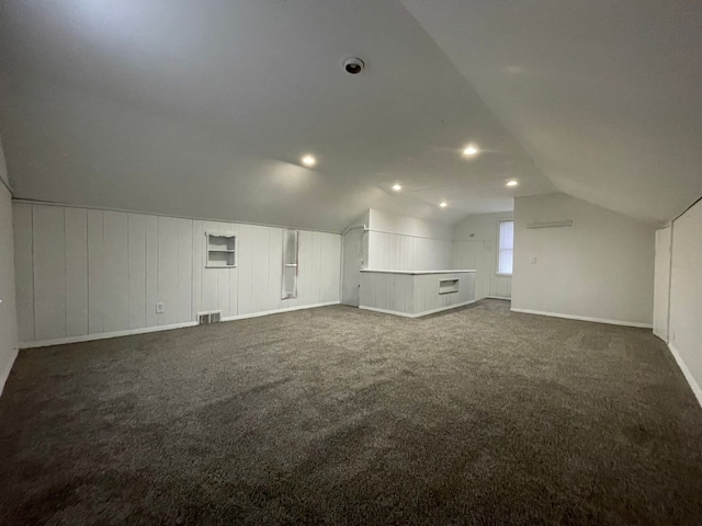 additional living space featuring dark colored carpet and vaulted ceiling