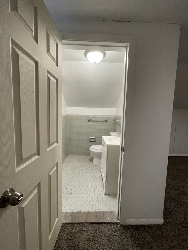 bathroom with tile patterned flooring, vanity, toilet, and tile walls