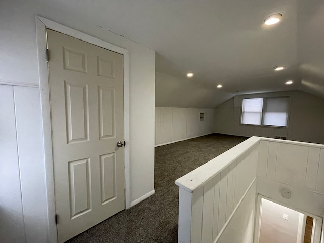 additional living space with dark colored carpet and lofted ceiling