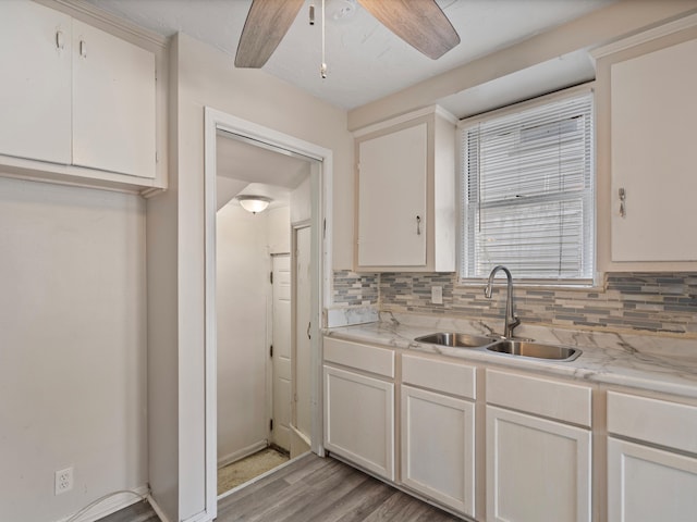 kitchen with tasteful backsplash, white cabinetry, sink, and light hardwood / wood-style floors