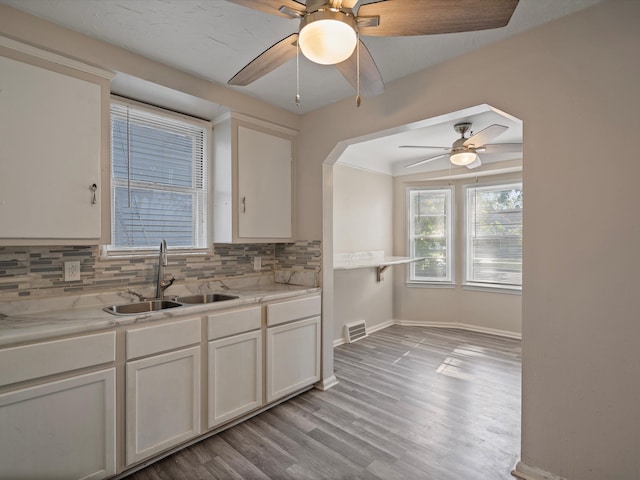 kitchen featuring white cabinetry, sink, ceiling fan, tasteful backsplash, and light wood-type flooring