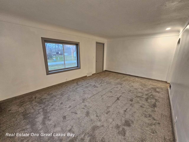 empty room featuring a textured ceiling and carpet floors