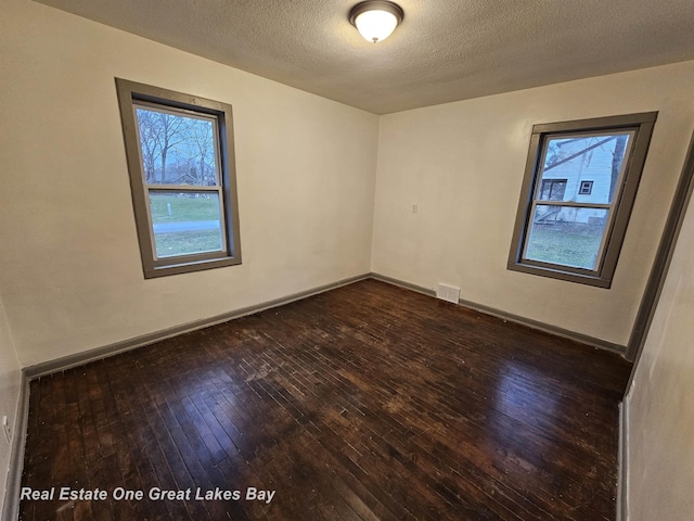 spare room with dark wood-type flooring and a textured ceiling