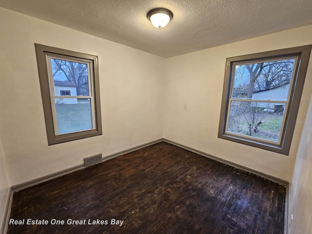 unfurnished room featuring dark hardwood / wood-style flooring, a wealth of natural light, and a textured ceiling