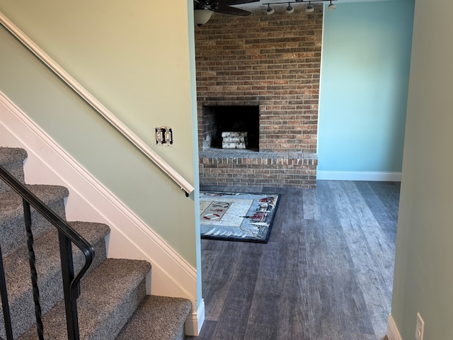 interior space featuring a fireplace, ceiling fan, and dark hardwood / wood-style flooring