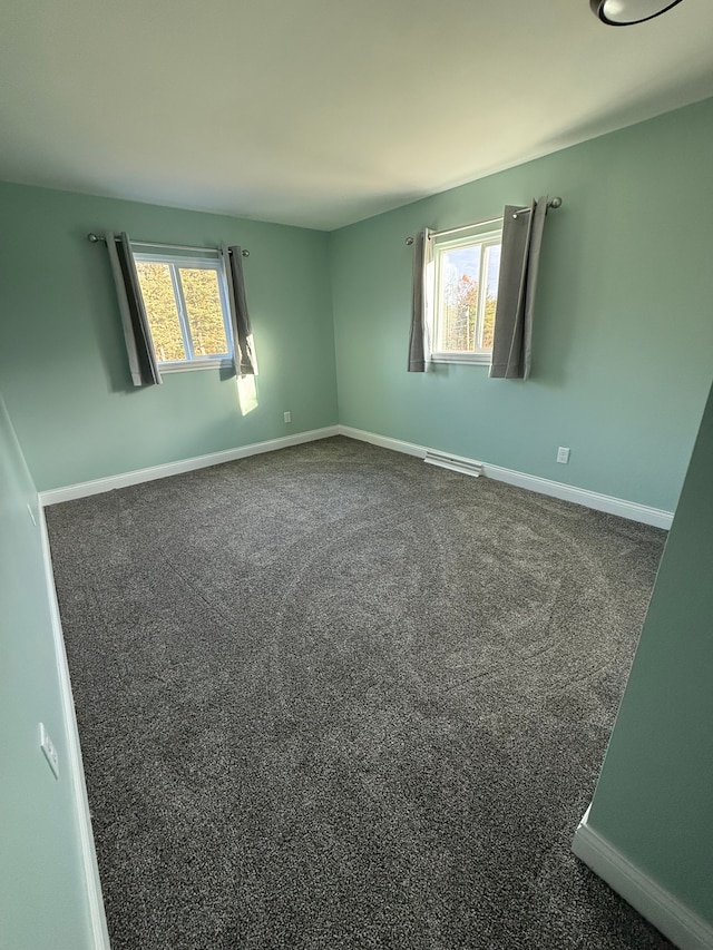 spare room with plenty of natural light and dark carpet