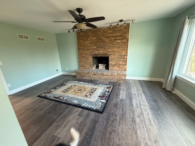 unfurnished living room featuring rail lighting, dark hardwood / wood-style floors, ceiling fan, and a fireplace