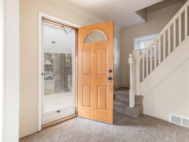 carpeted entrance foyer featuring a wealth of natural light and ornamental molding