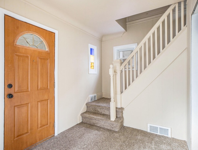 foyer entrance with carpet floors and crown molding