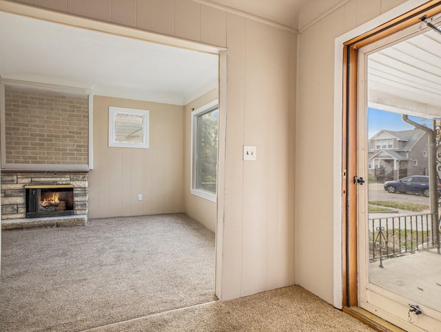 doorway to outside with carpet, ornamental molding, a fireplace, and a wealth of natural light