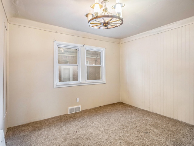 spare room featuring carpet flooring and a chandelier