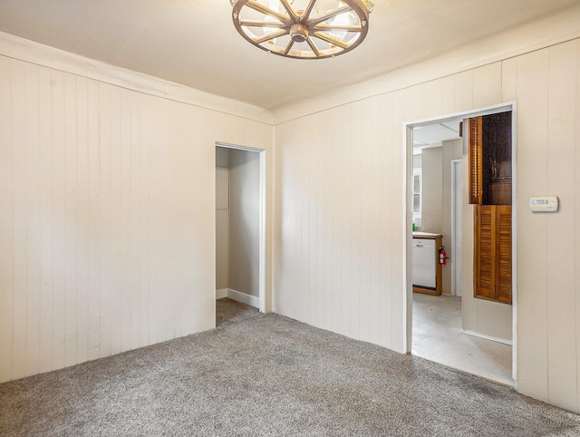 carpeted spare room with wooden walls