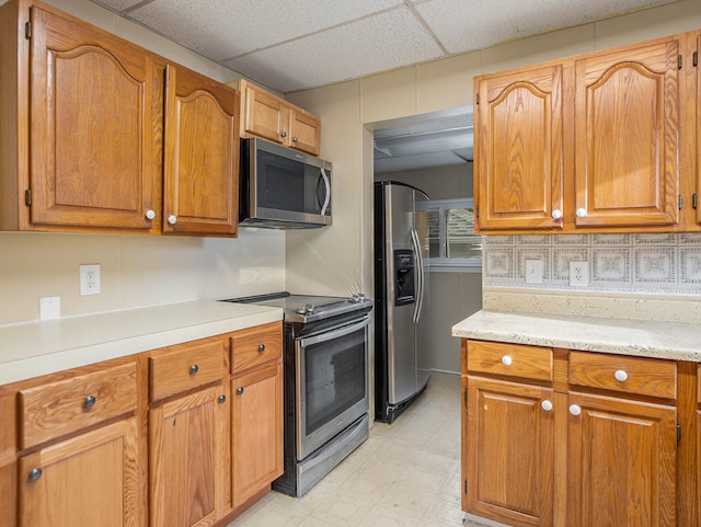 kitchen featuring tasteful backsplash, a drop ceiling, and stainless steel appliances