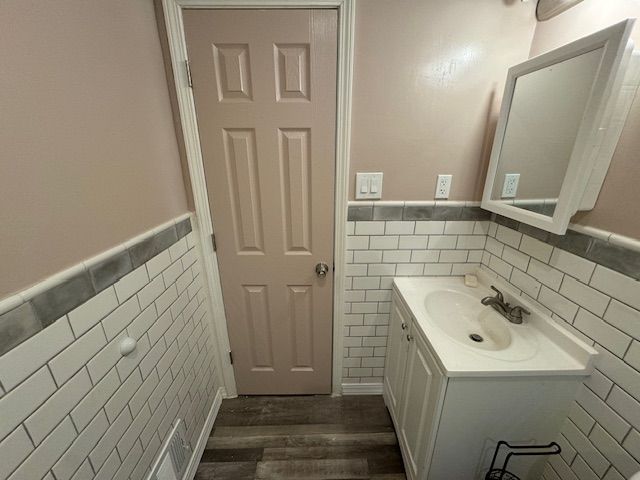 bathroom with tile walls, vanity, and hardwood / wood-style flooring