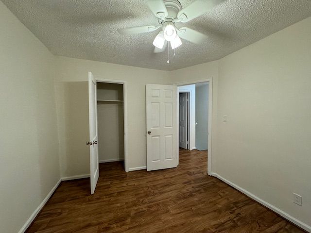 unfurnished bedroom with a closet, dark hardwood / wood-style floors, a textured ceiling, and ceiling fan