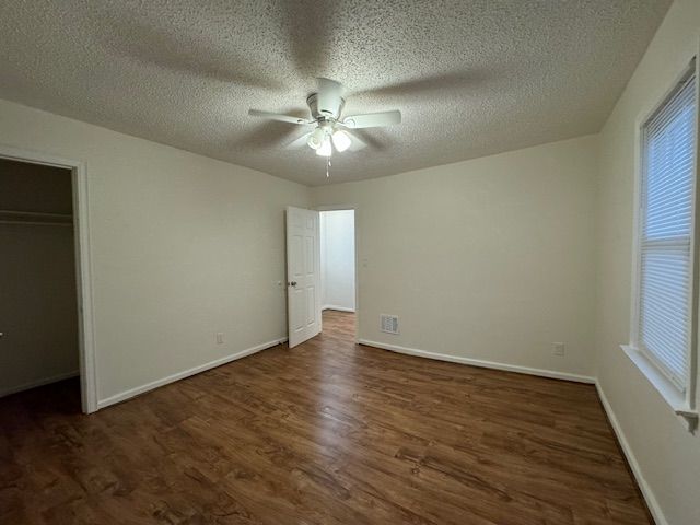 unfurnished bedroom with dark wood-type flooring, ceiling fan, a closet, and a textured ceiling