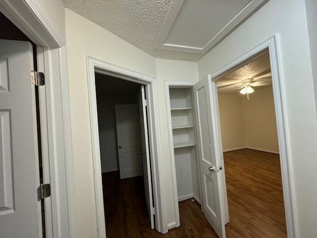 corridor featuring dark wood-type flooring and a textured ceiling