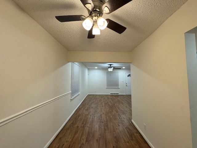 bonus room with dark wood-type flooring and a textured ceiling