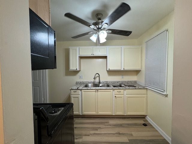 kitchen featuring sink, white cabinets, range, light hardwood / wood-style floors, and light stone countertops