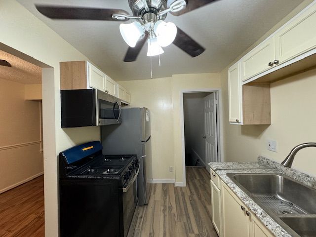 kitchen featuring hardwood / wood-style floors, black gas range, ceiling fan, and sink