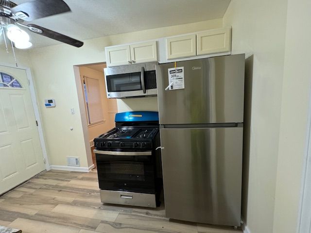 kitchen with white cabinetry, ceiling fan, appliances with stainless steel finishes, and light hardwood / wood-style flooring