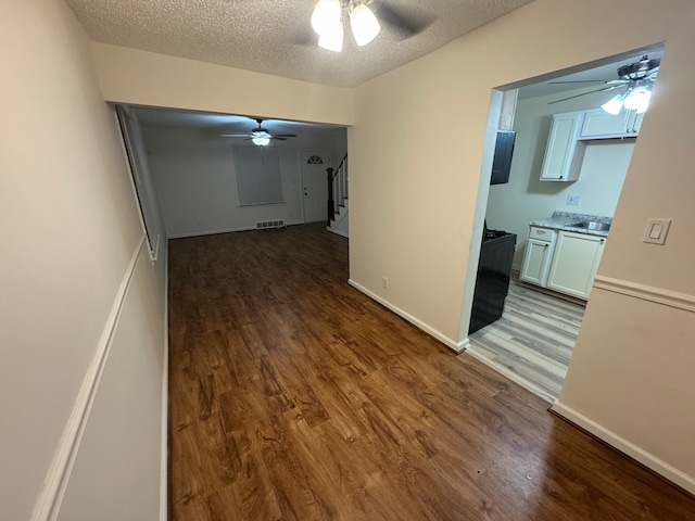 hallway with dark hardwood / wood-style flooring, sink, and a textured ceiling