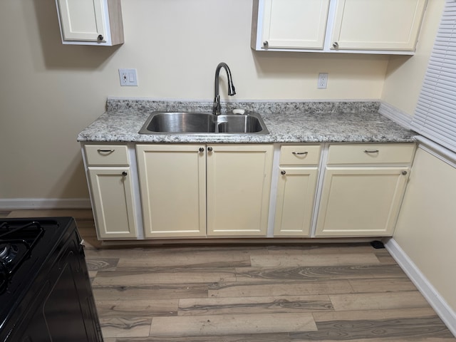 kitchen with light stone counters, wood-type flooring, and sink