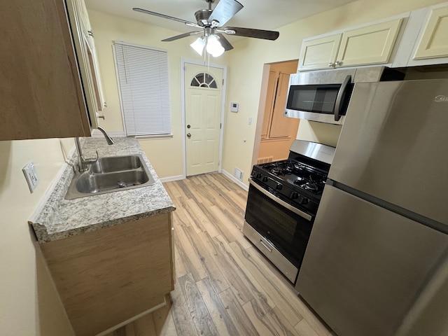 kitchen with ceiling fan, appliances with stainless steel finishes, sink, and light wood-type flooring