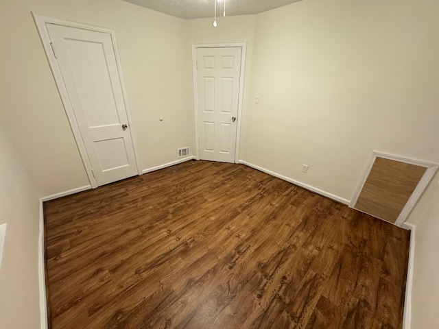 unfurnished room with a textured ceiling and dark hardwood / wood-style flooring