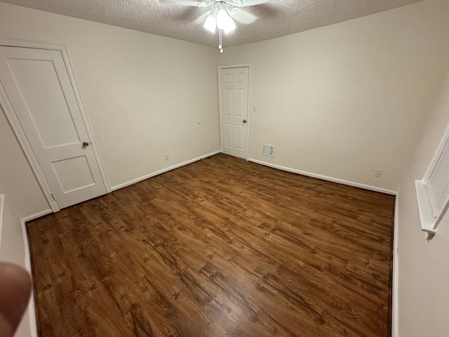 unfurnished bedroom featuring ceiling fan, dark hardwood / wood-style floors, and a textured ceiling