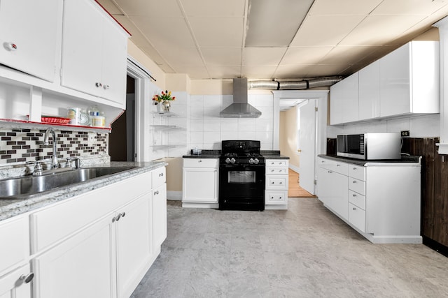 kitchen with white cabinets, sink, wall chimney exhaust hood, decorative backsplash, and black gas range oven