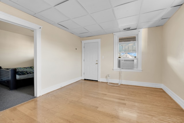 empty room with a drop ceiling, cooling unit, and light wood-type flooring