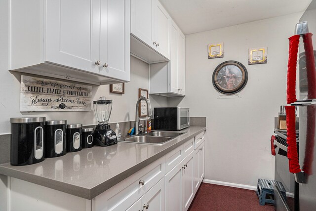 kitchen featuring sink, white cabinets, and dark carpet