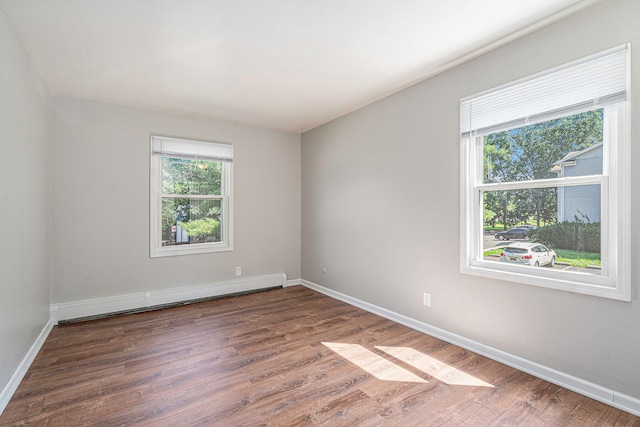 unfurnished room with dark hardwood / wood-style flooring and baseboard heating