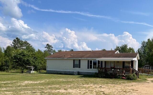 back of property featuring covered porch and a lawn