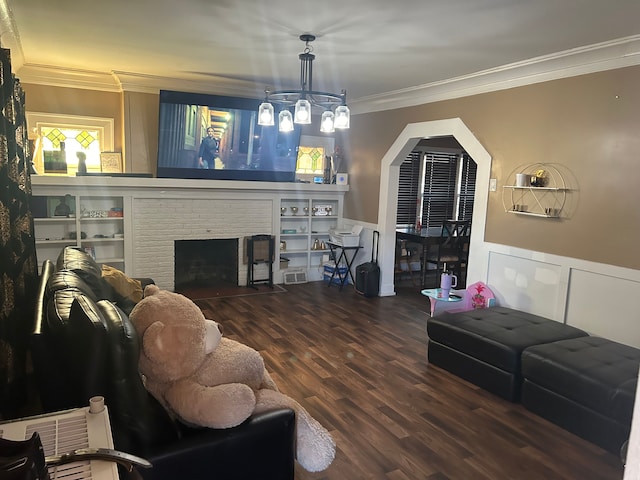 living room featuring hardwood / wood-style floors, built in shelves, ornamental molding, and a fireplace