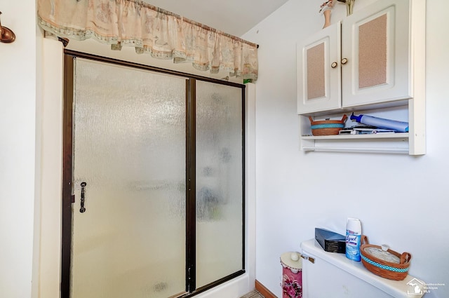 bathroom with a shower with door and toilet