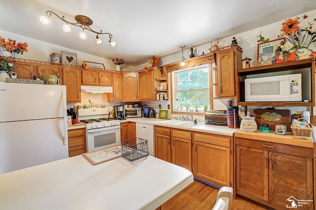 kitchen with white appliances, light hardwood / wood-style flooring, lofted ceiling, and sink