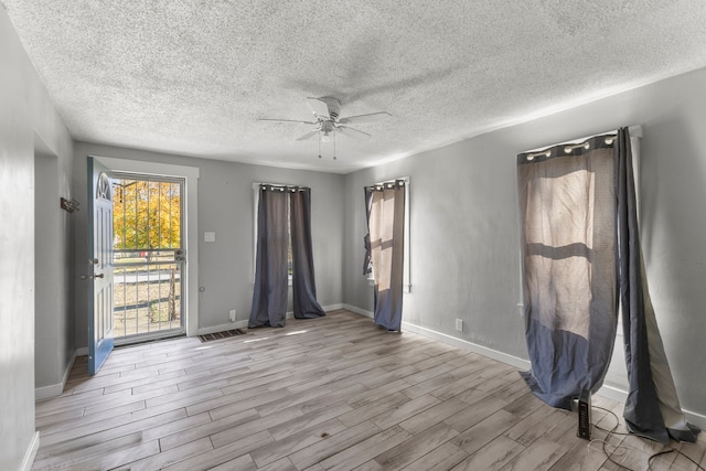 spare room featuring a textured ceiling, light wood-type flooring, and ceiling fan