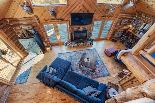 living room with a stone fireplace, high vaulted ceiling, and hardwood / wood-style flooring