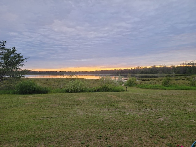 yard at dusk featuring a water view