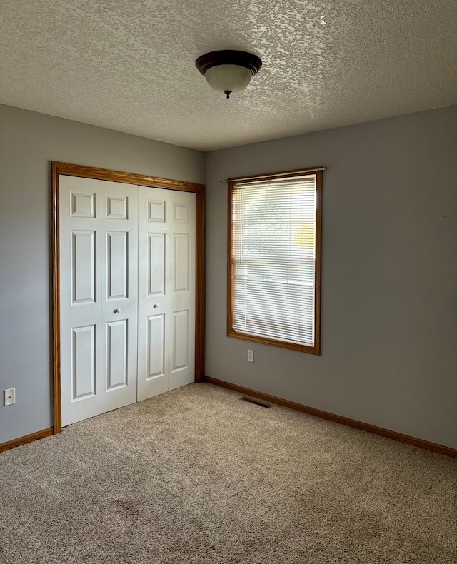 unfurnished bedroom featuring carpet flooring, a closet, and a textured ceiling