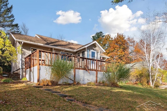 rear view of property featuring a lawn and a deck