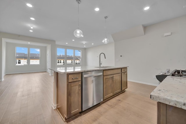 kitchen with sink, a kitchen island with sink, light stone countertops, decorative light fixtures, and stainless steel dishwasher